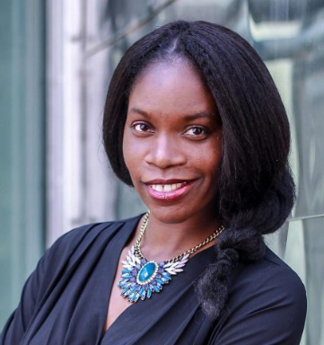 Jacqueline Shaw smiling wearing a navy dress and ornate blue and purple Eygptian style winged necklace