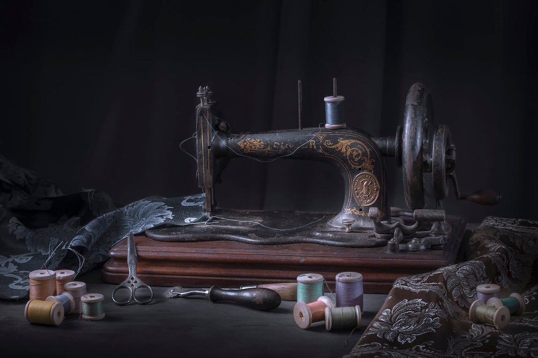 Old Victorian sewing machine with fabric and brightly coloured thread scattered nearby