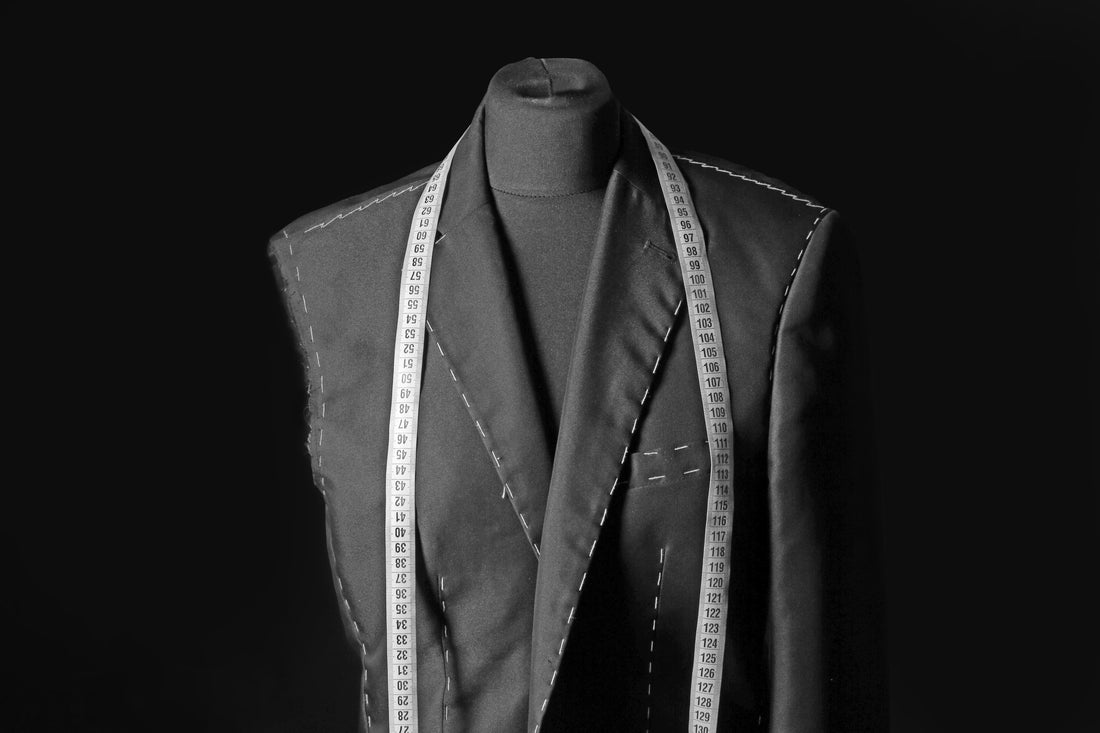 Tailor's suit jacket toile with exposed white stitching on the bodice and tape measure draped around the neckline