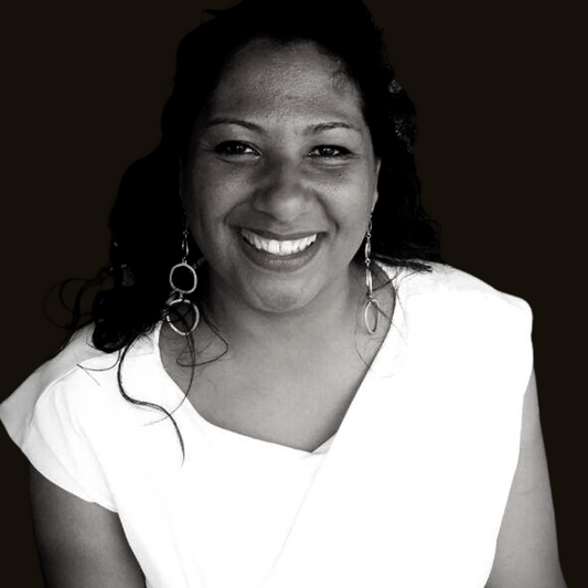Anna Marie Benedict smiling and wearing a white t-shirt and drop hoop earrings