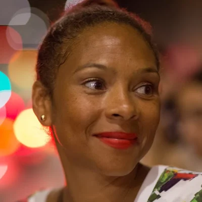 Charlotte Smith with red lipstick wearing gold stud earrings and a multicoloured top