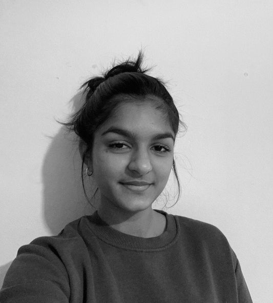 Siyona Parekh with her hair up in a bun and wearing a dark round neck jumper